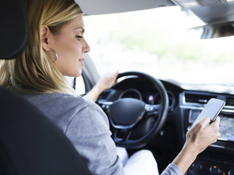 Frau mit Handy im Auto