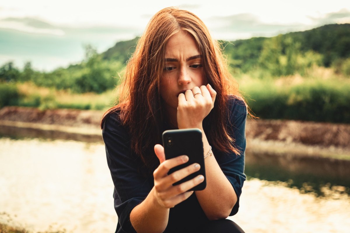 Frau schaut besorgt auf ihr Handy.