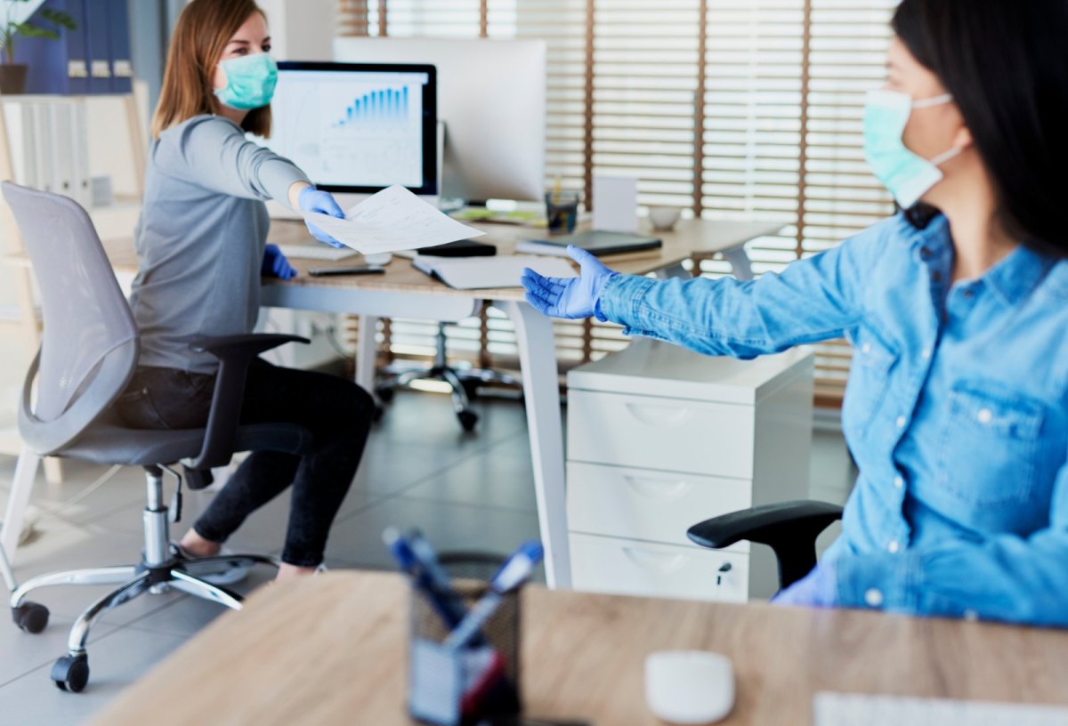 Zwei Frauen mit Maske in einem Büro.