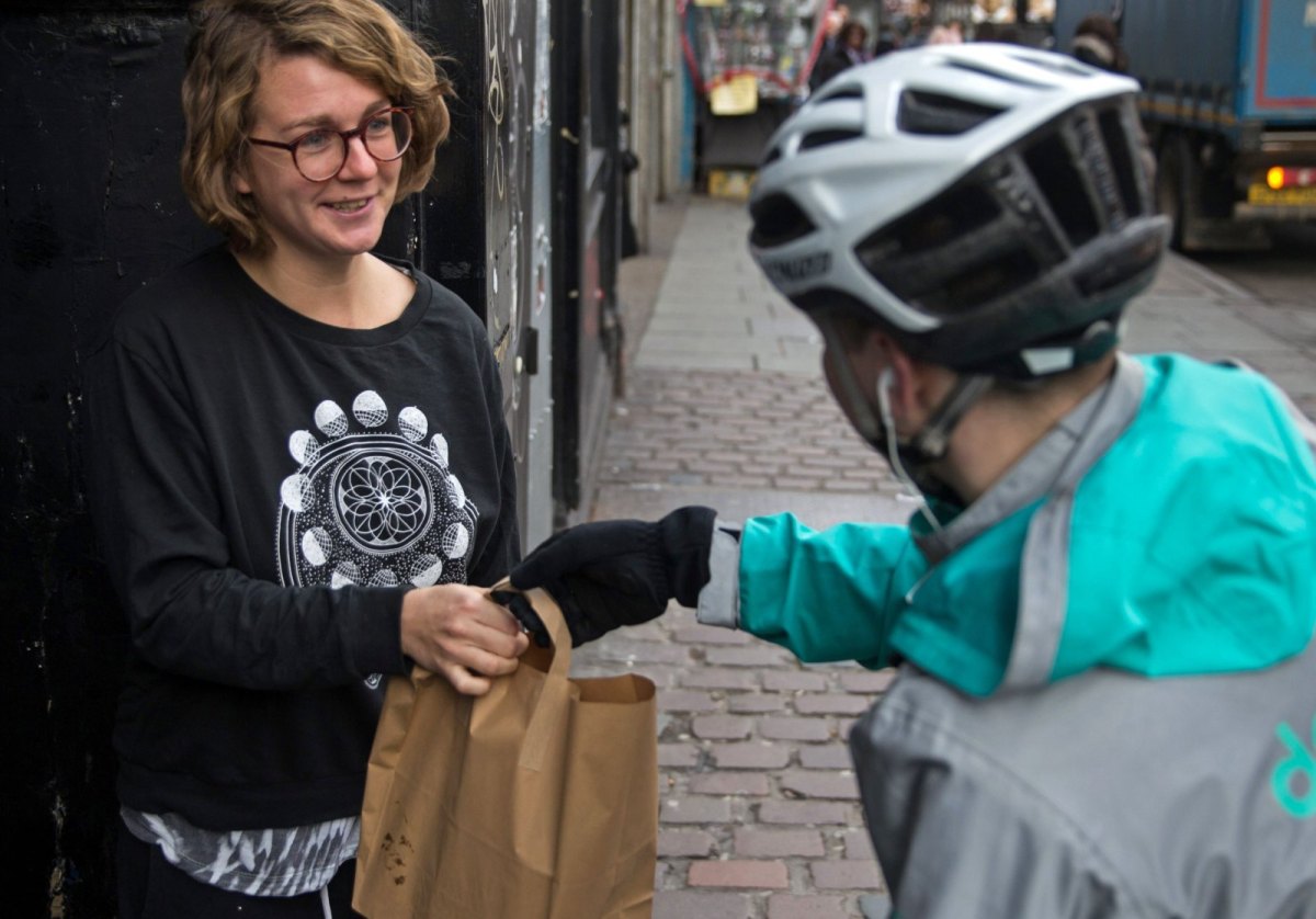 Ein Deliveroo-Fahrer beliefert eine Kundin.