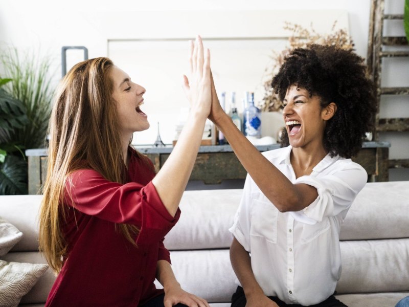 Zwei junge Frauen lachen und geben sich High-Five