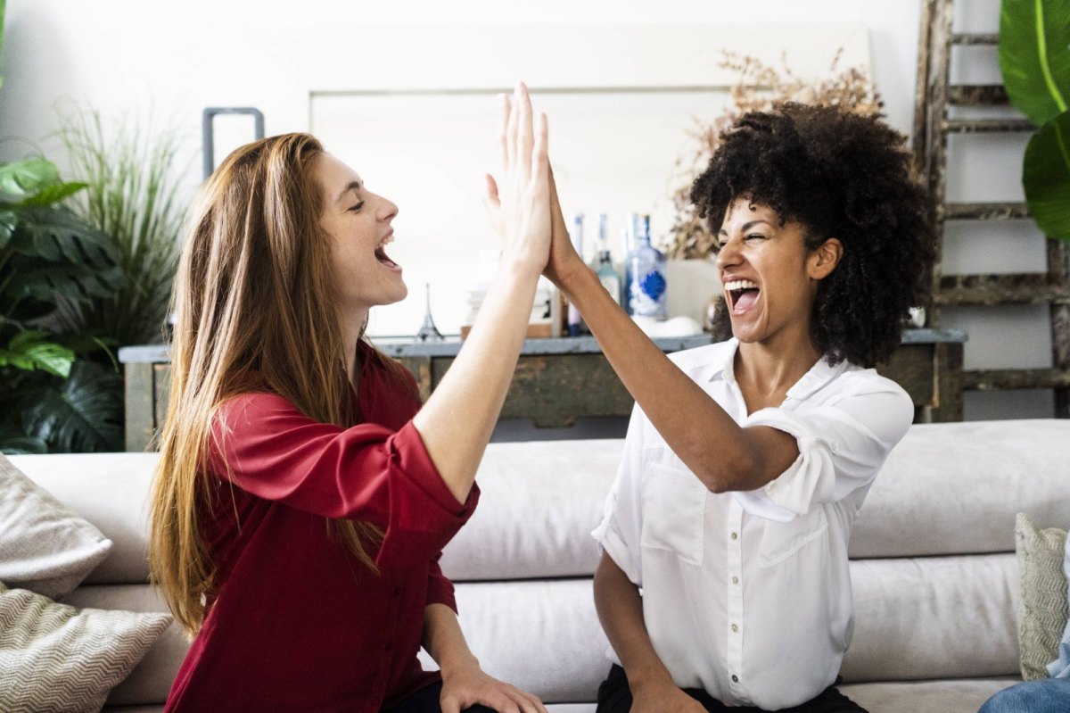 Zwei junge Frauen lachen und geben sich High-Five