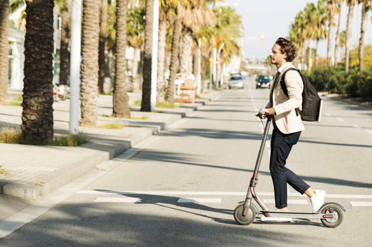 Mann fährst auf E-Scooter.