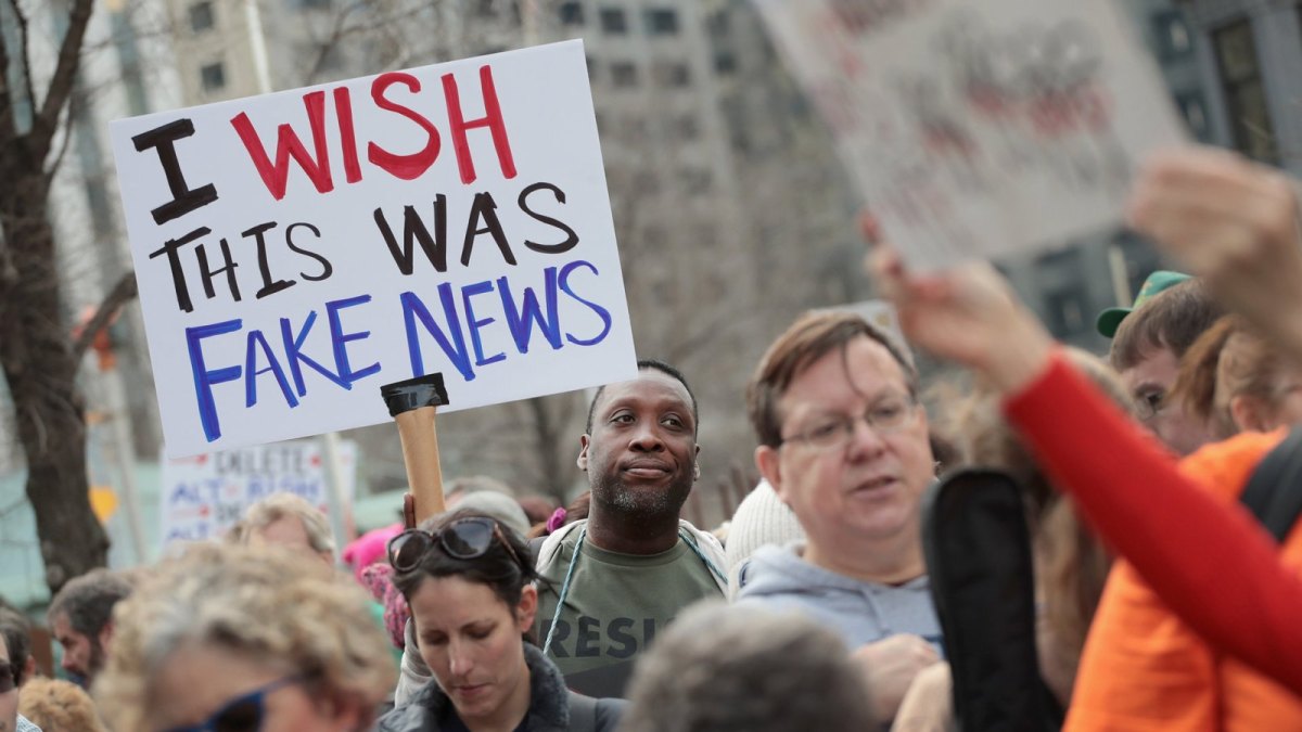 Mann hält ein Schild hoch mit: "I wish this was fake news".