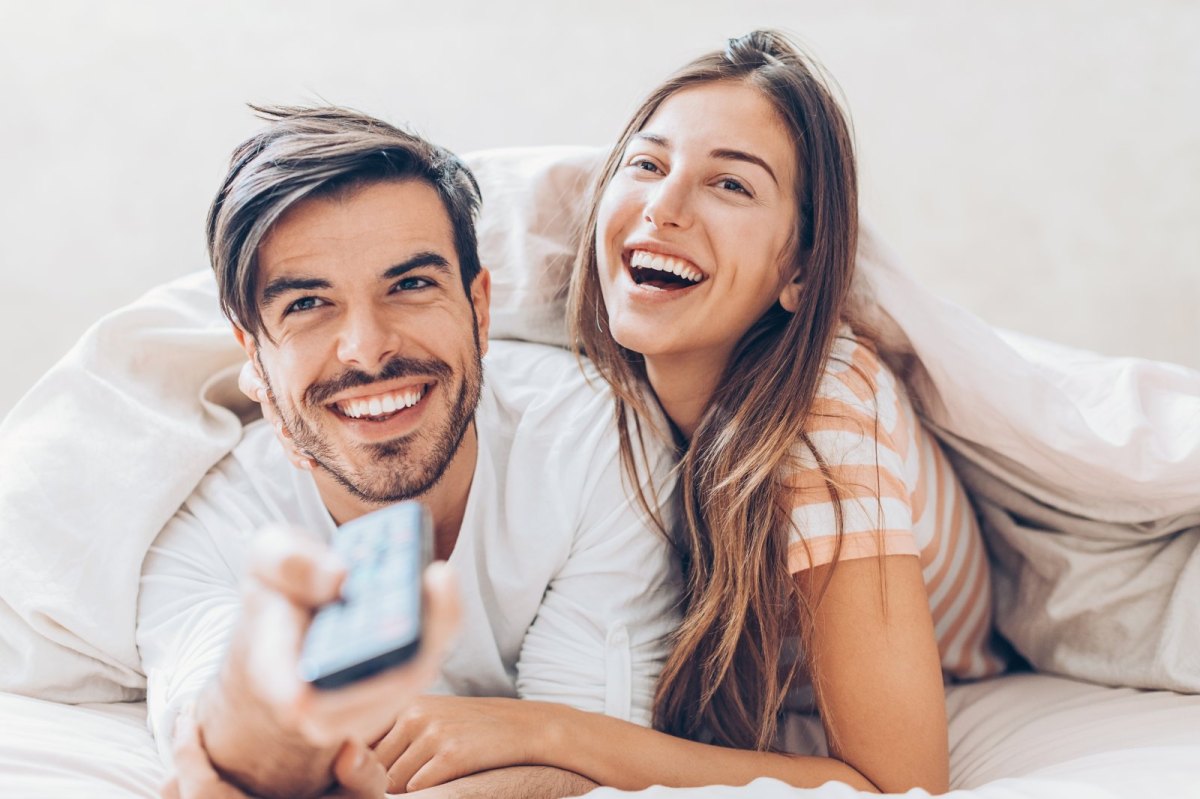 Mann und Frau im Bett mit Fernbedienung