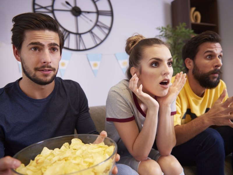 Überraschte Menschen vor dem Fernseher