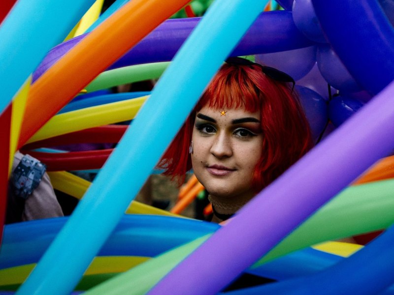 Frau mit roter Perücke in bunten Luftballons