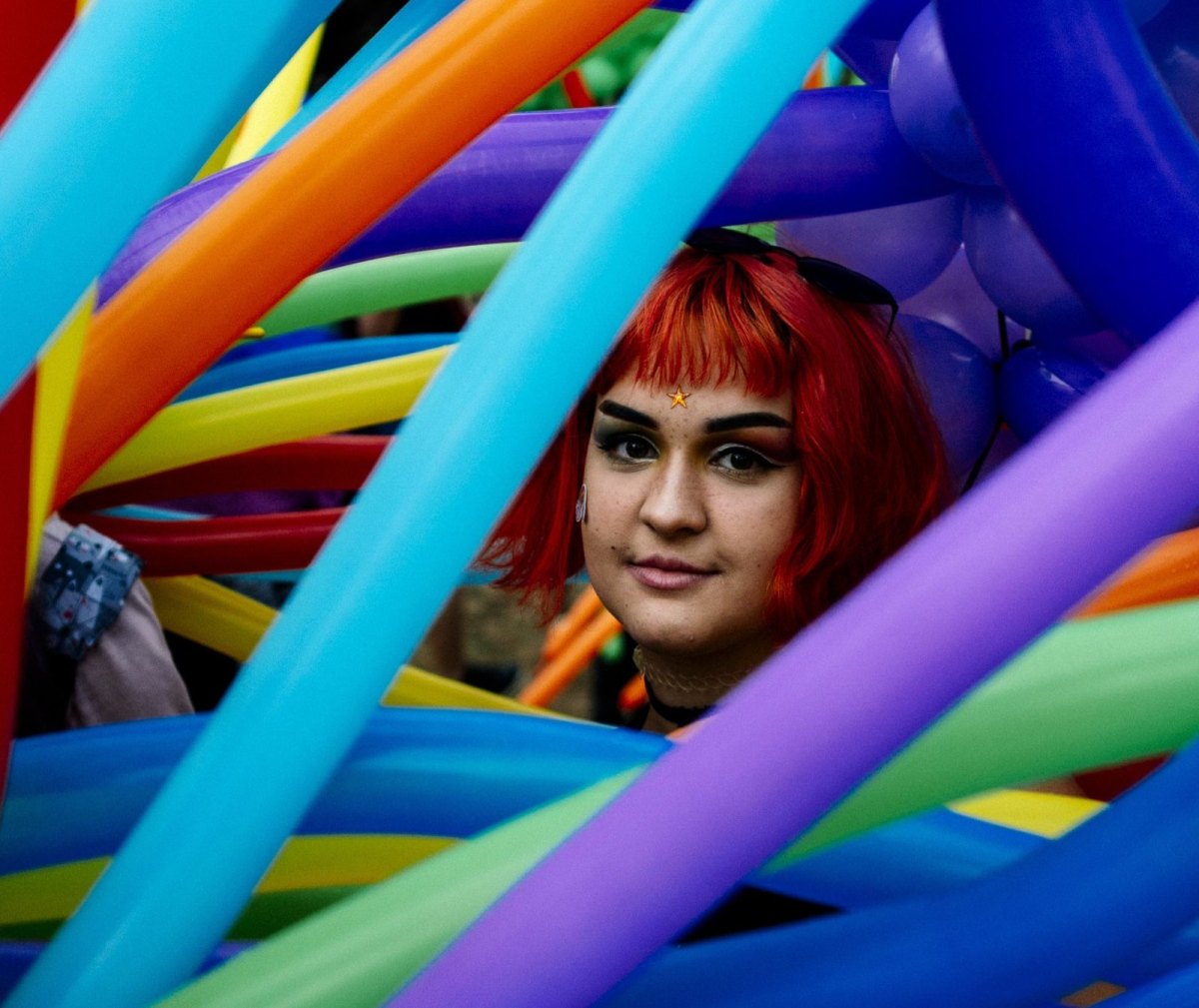 Frau mit roter Perücke in bunten Luftballons