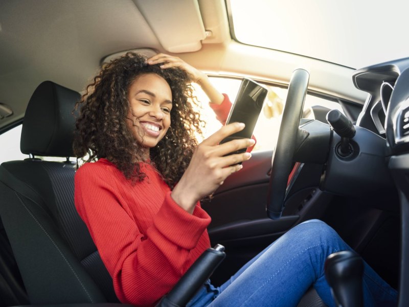 Frau mit Handy im Auto