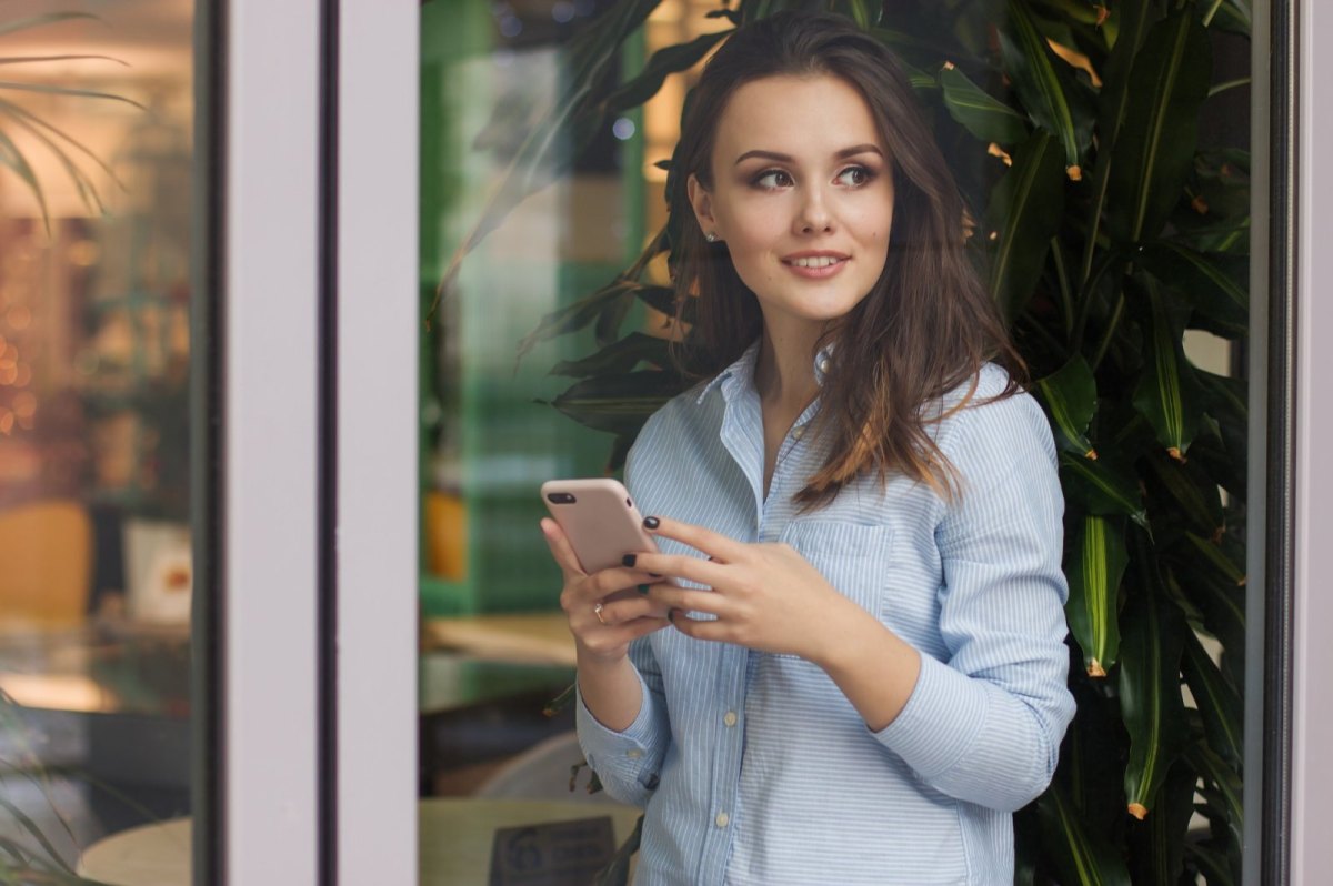 Frau hält Smartphone in der Hand und lacht.