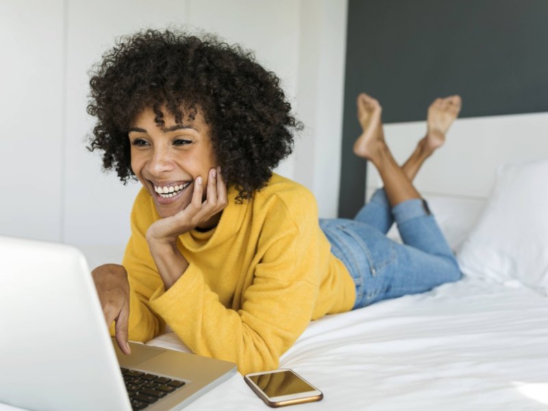 Frau auf dem bett schaut einen Filmauf den Laptop