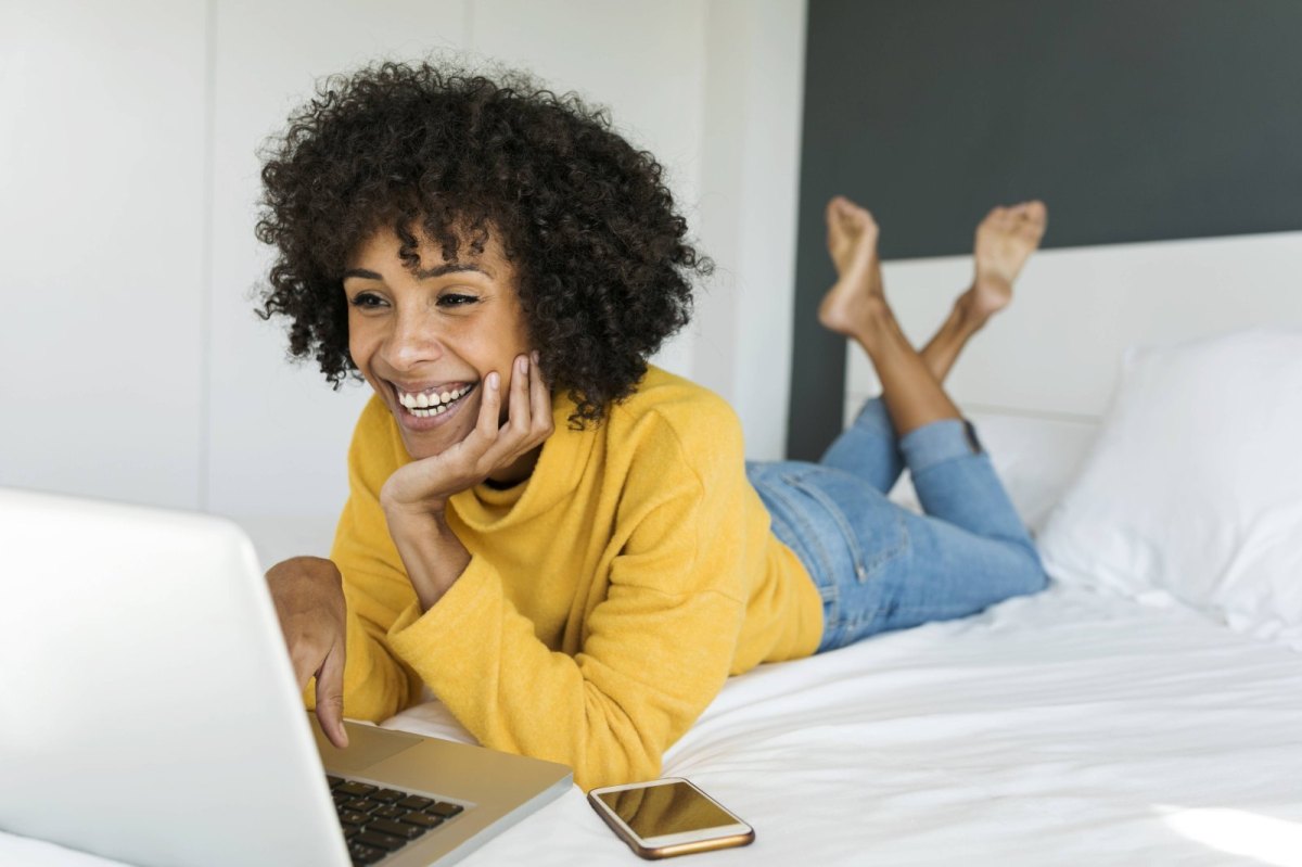 Frau auf dem bett schaut einen Filmauf den Laptop