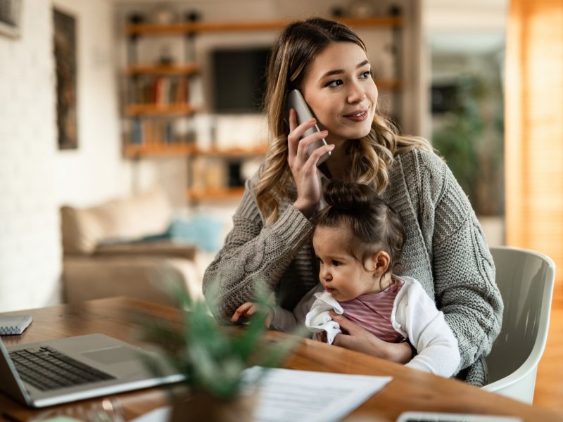 Frau mit Kind und schnurlosem Telefon.