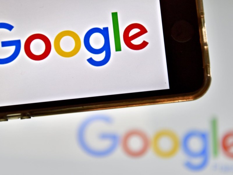 Google-Logo auf Smartphone-Display und im Hintergrund