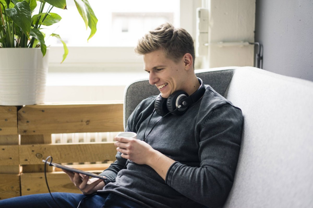 Mann mit Kopfhörern und Tablet.