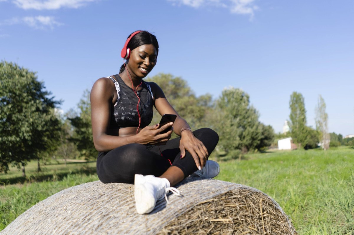 Frau in Sportoutfit mit Handy und Kopfhörern.