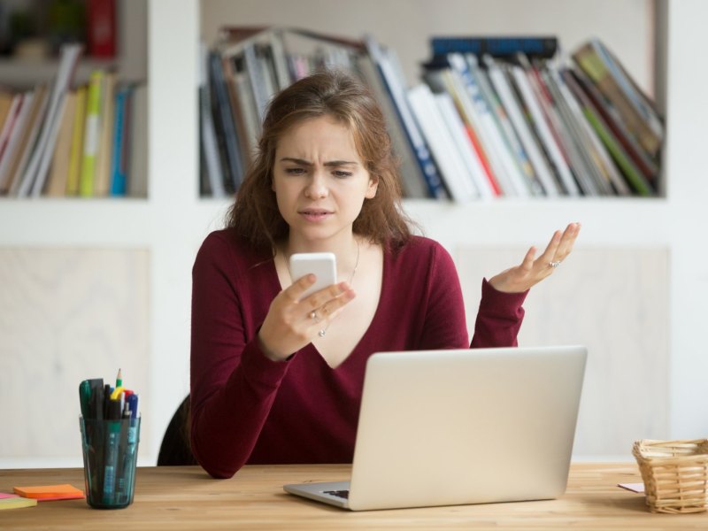 Frau schaut sauer auf ihr iPhone