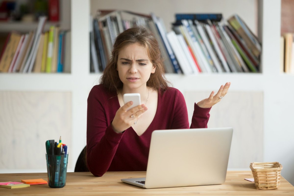 Frau schaut sauer auf ihr iPhone