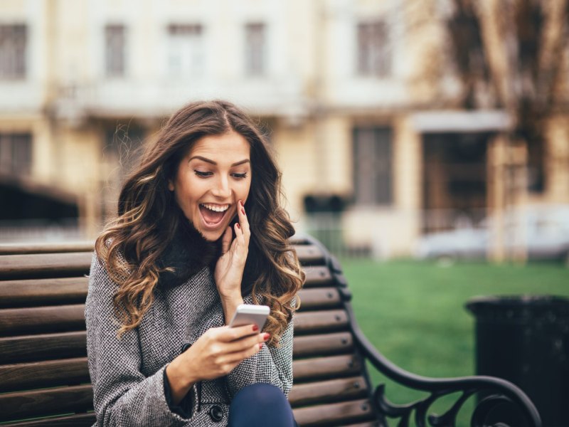 Frau schaut überrascht auf ihr Handy