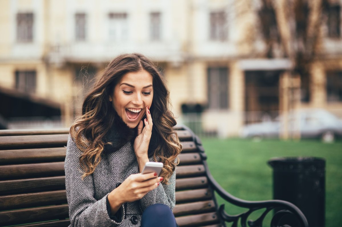 Frau schaut überrascht auf ihr Handy