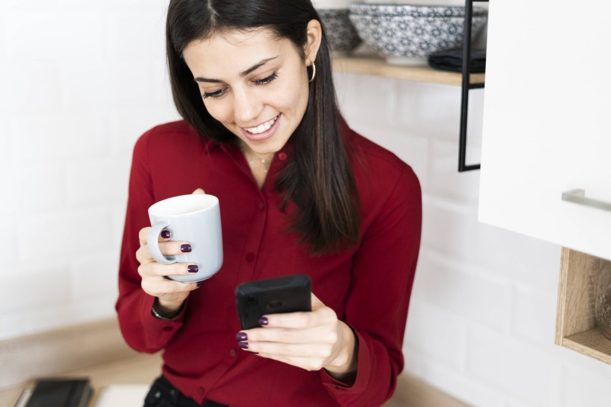 Frau schaut lächelnd auf ihr Handy