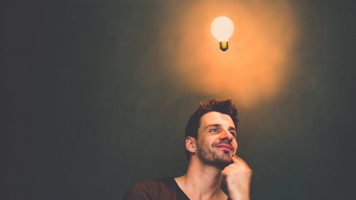 Nachdenkender Mann mit einer leuchtenden Glühlampe über dem Kopf