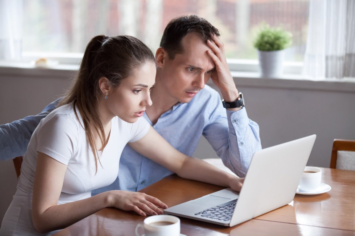 Mann und Frau starren geschockt auf einen Laptop.