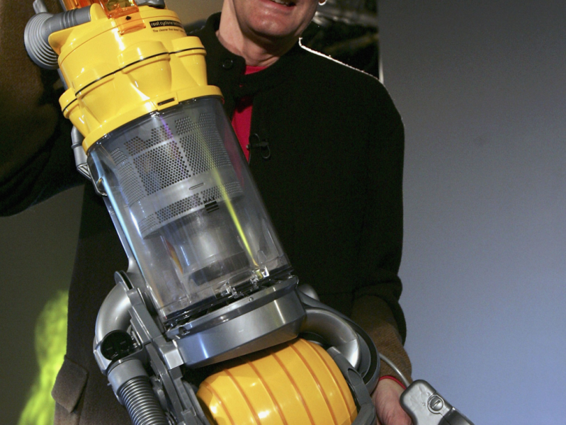 Dyson-Gründer James Dyson hält einen Dyson Staubsauger hoch