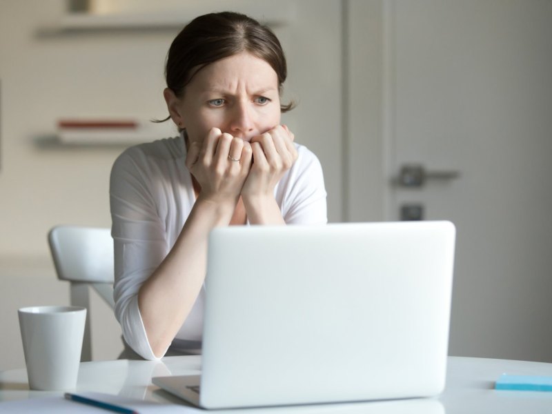 Frau sitzt besorgt vor dem Laptop.