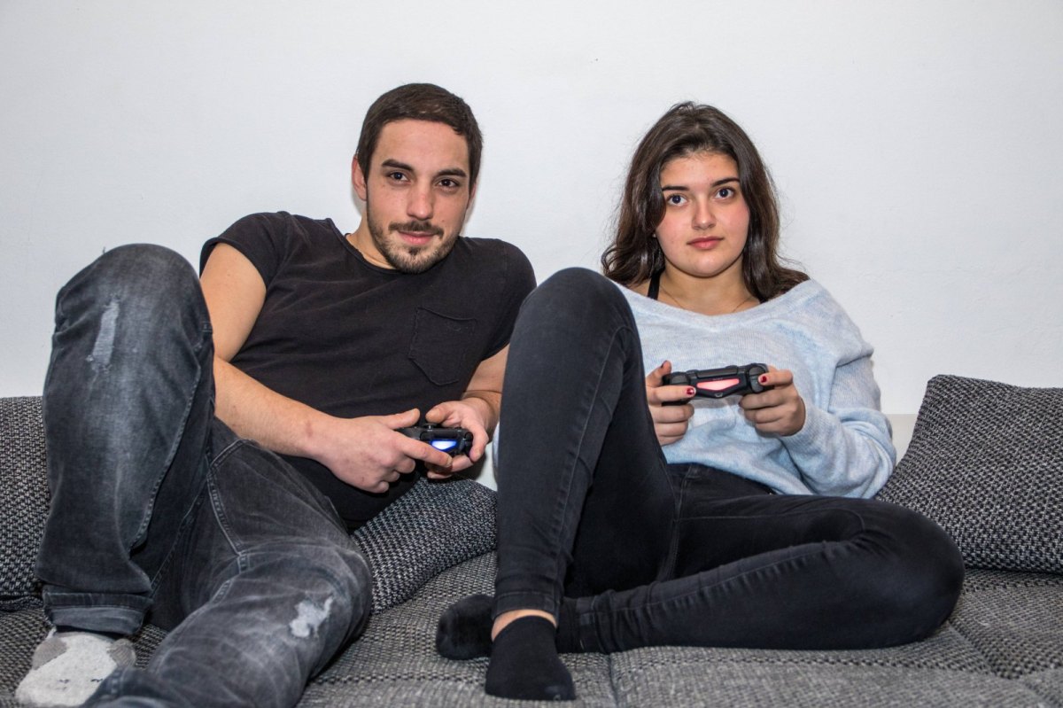 Junger Mann und Teenager Mädchen spielen mit PlayStation 4 Controllern auf Couch daheim Videospiele spielen auf Konsole