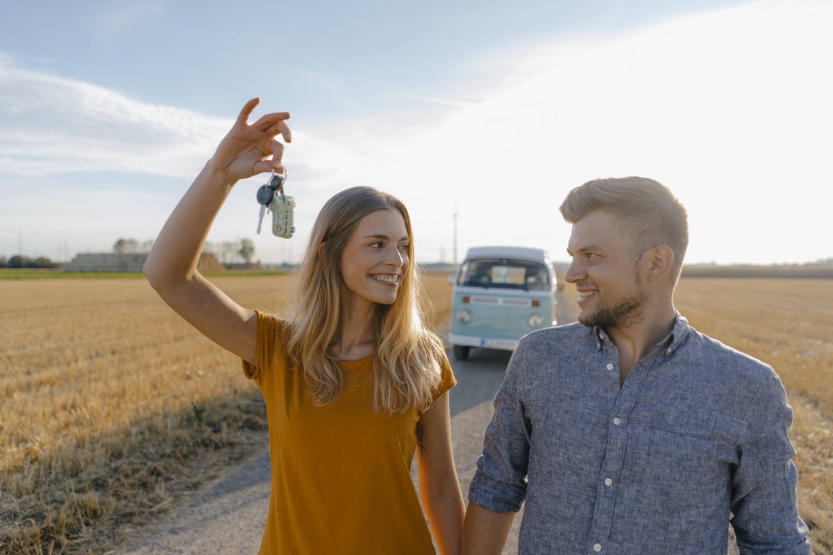 Eine Frau und ein Mann spazieren über ein Feld. Die Frau hält einen Schlüssel in die Luft.