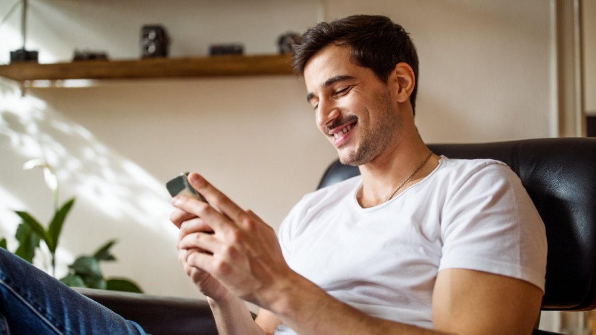 Mann mit kleinem Smartphone in der Hand.