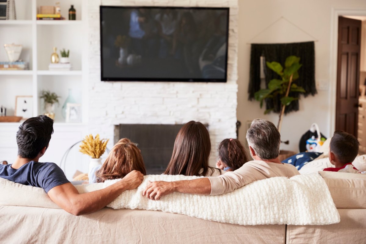 Familie sitzt vor einem Fernseher auf dem Sofa