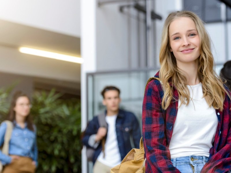 Junge Studentin lächelt und blickt zuversichtlich in die Zukunft.