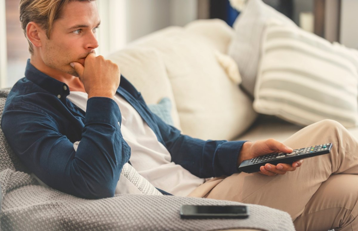 Mann auf dem Sofa mit Fernbedienung