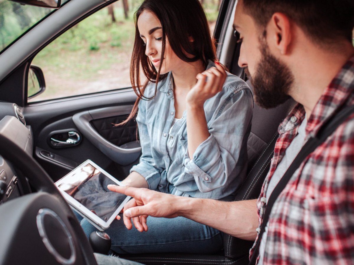 Mann und Frau sitzen mit Tablet im Auto