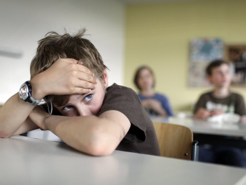 Das Bild zeigt einen traurigen Junge in der Schule