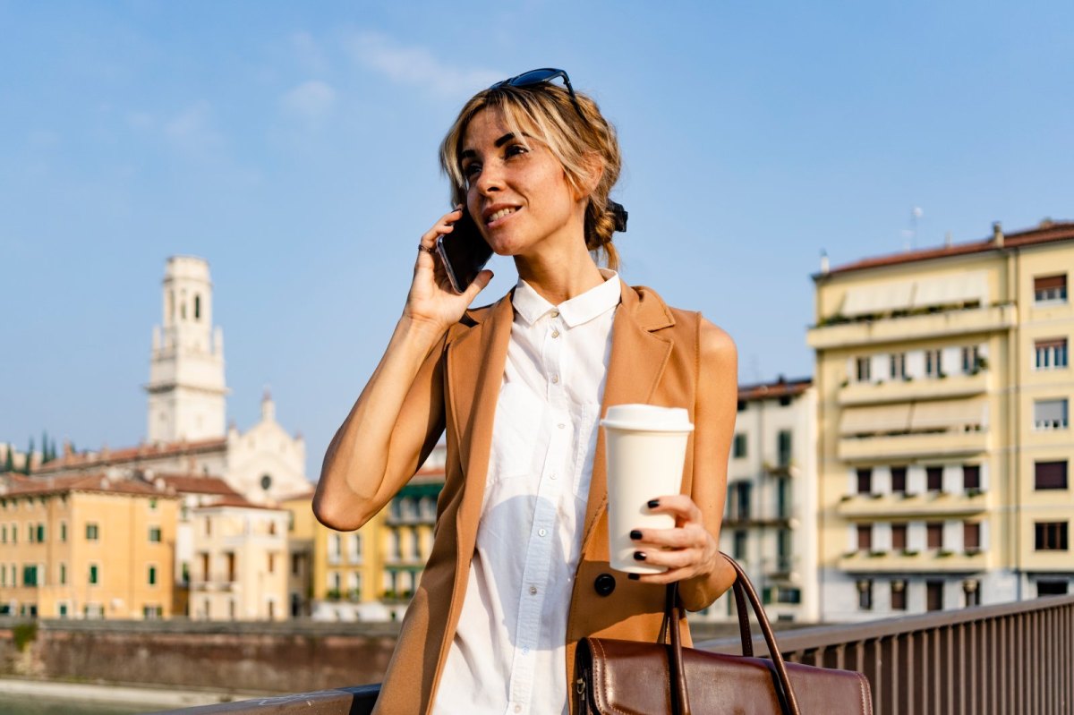 Frau telefoniert mit Kaffeebecher in der Hand.