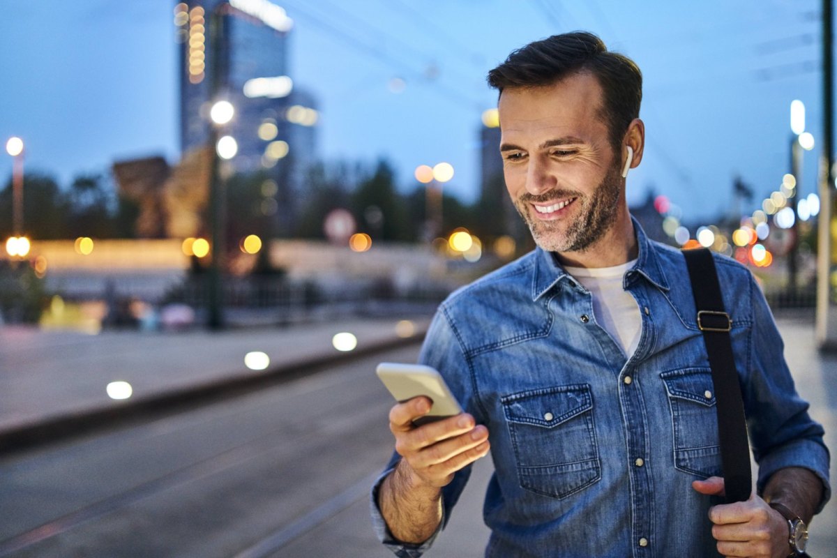 Mann guckt glücklich auf sein Handy