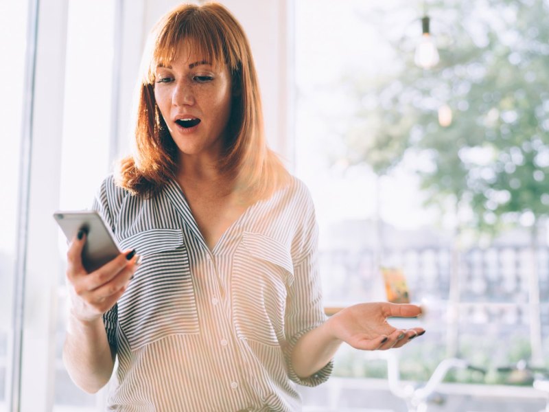 Frau am Handy schockiert