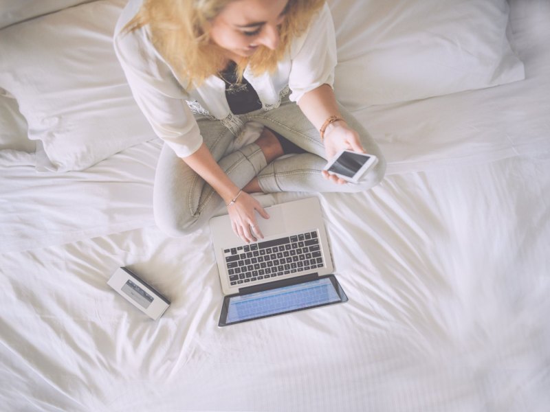 Frau sitzt am Laptop mit Handy