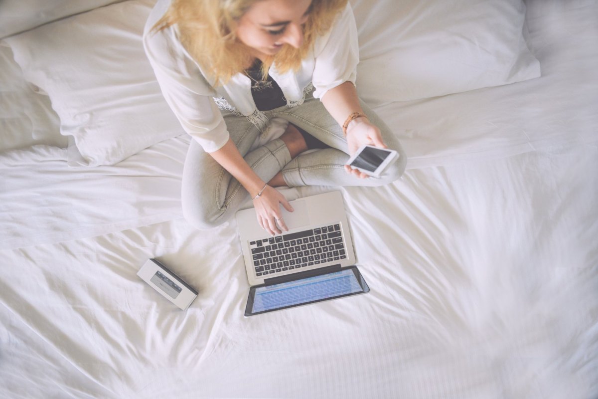 Frau sitzt am Laptop mit Handy