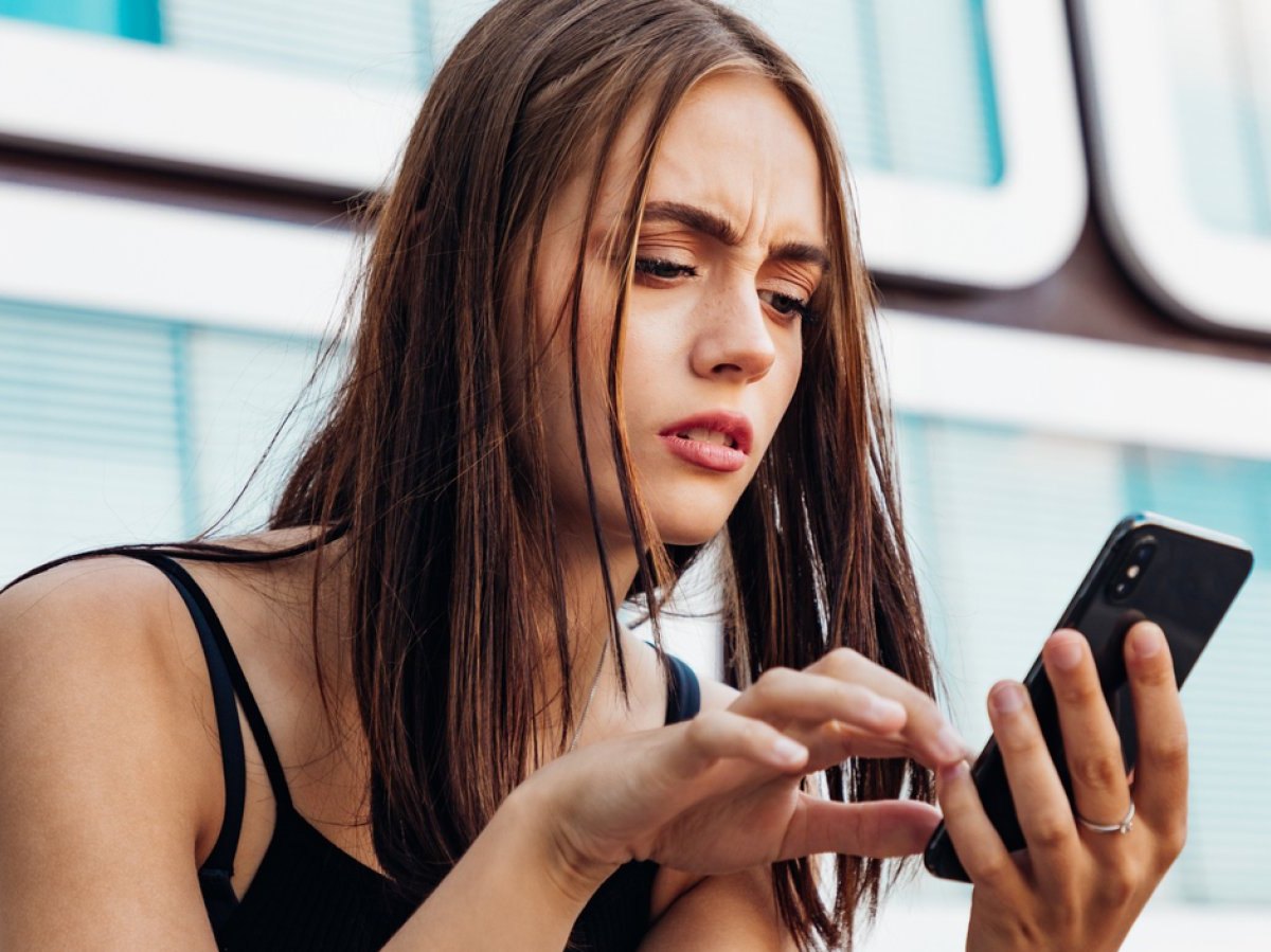 Frau blickt besorgt auf ihr Handy.