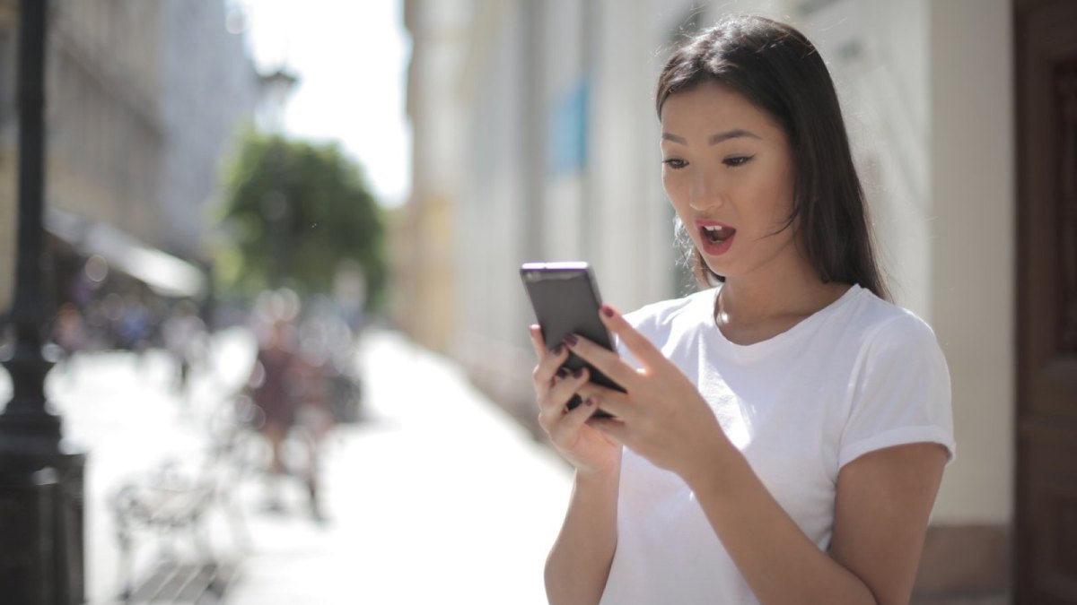 Eine Frau schaut erstaunt auf ihr Smartphone.