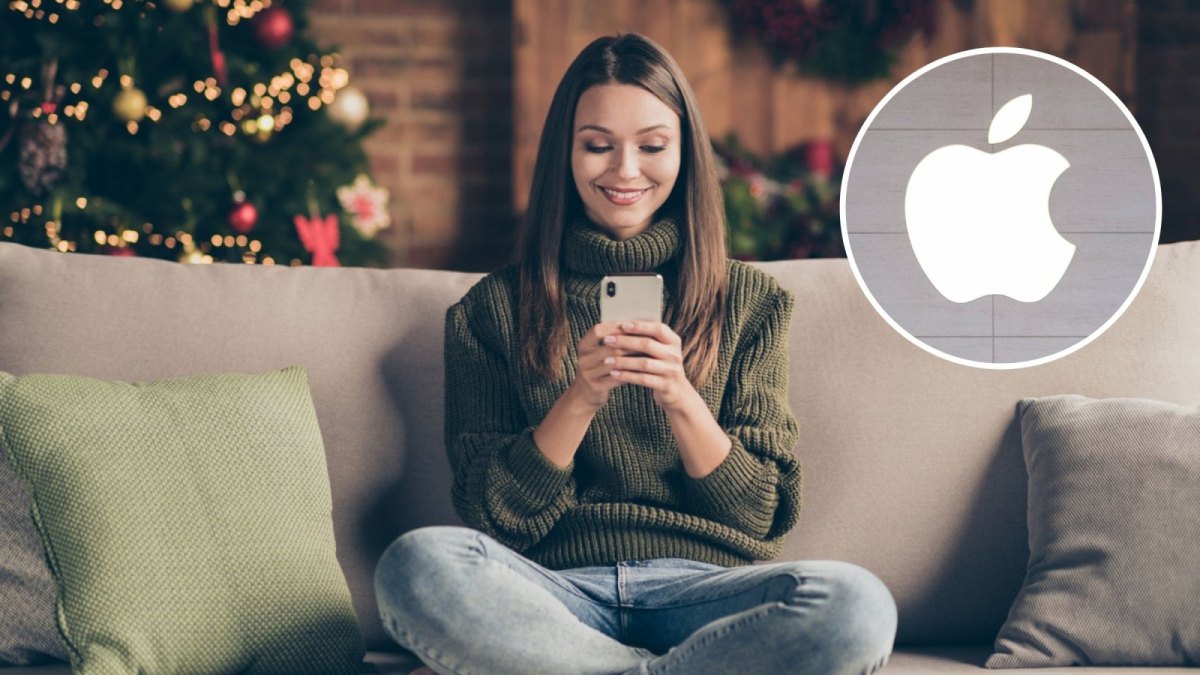 Frau mit Handy auf dem Sofa. Hinter ihr ein Weihnachtsbaum