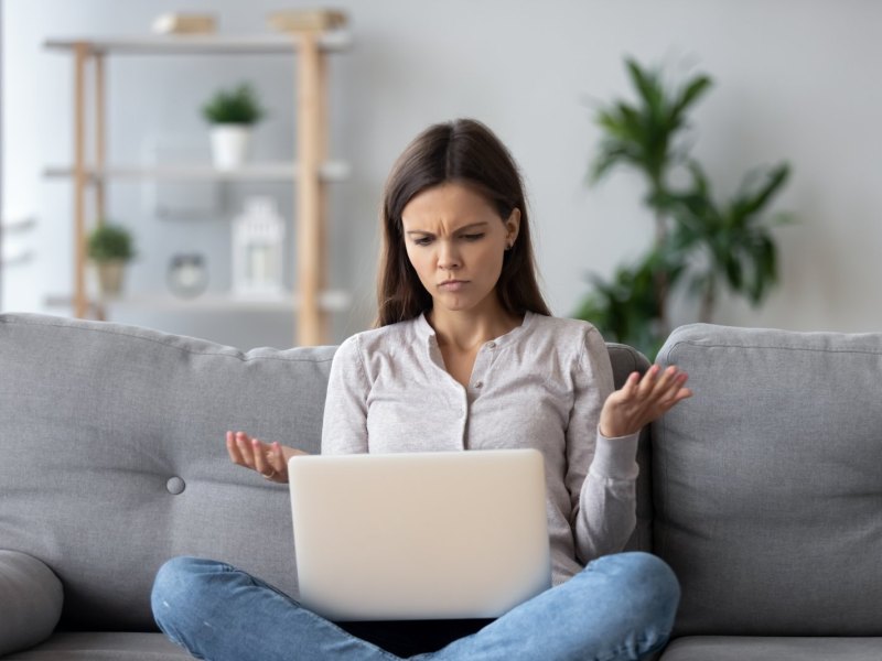 Frau schaut genervt auf Laptop.