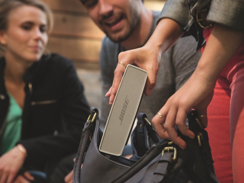 Eine Frau holt eine portable Bose-Box aus ihrer Tasche.