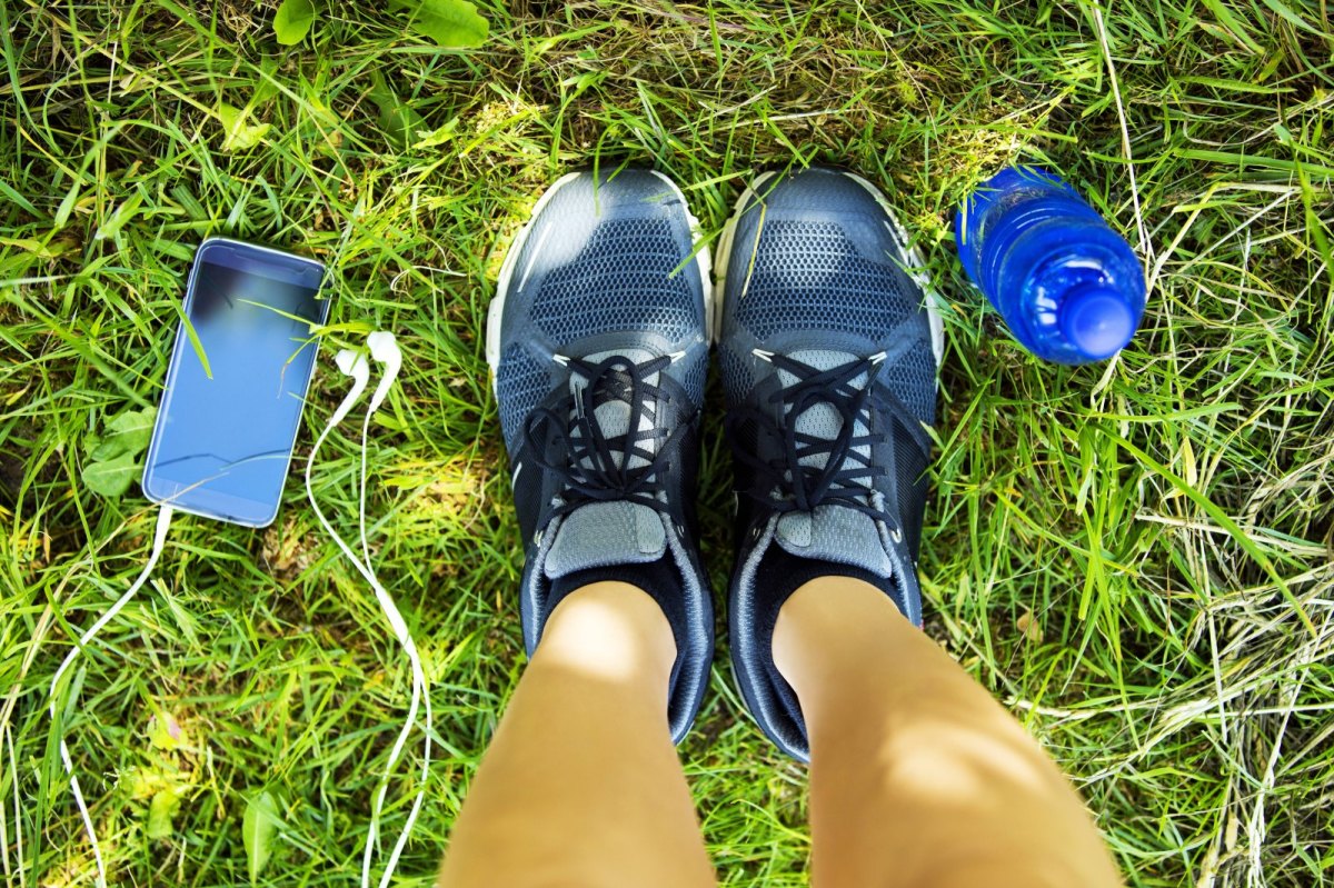 Person mit Sportschuhe steht im Gras