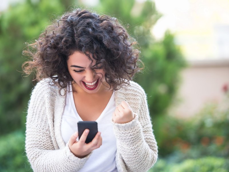 Frau freut sich über ihrem Handy.