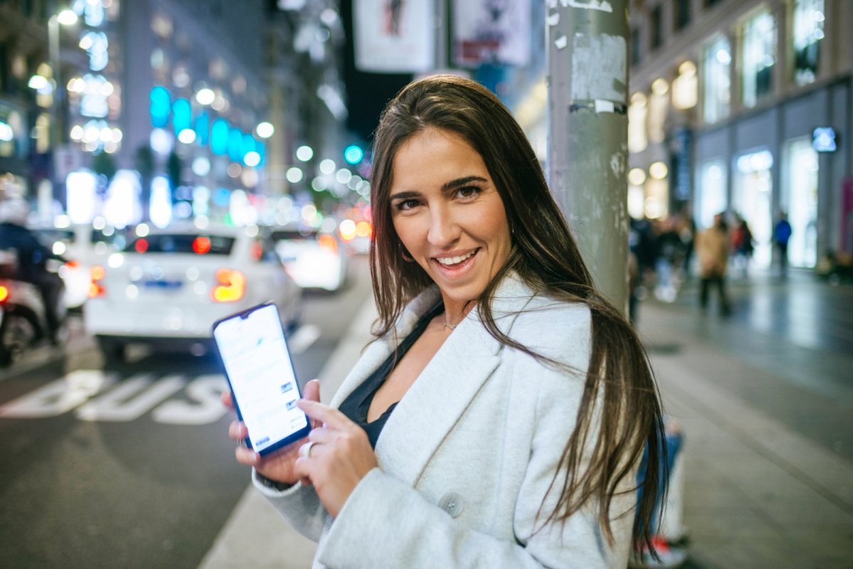 Frau zeigt auf smartphone und lächelt